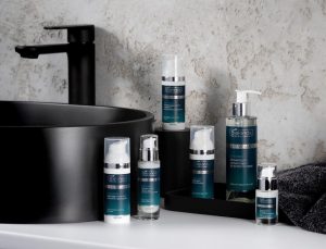 Bottles of men's skincare products from Bielenda Supremelab, lined up on a bathroom counter next to a black sink.