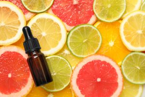 A brown glass bottle with a pipette lies on a bed of sliced grapefruit, limes, oranges and lemons.